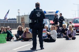 Ein Polizist beobachtet Klimaaktivisten auf der Dresdner Carolabrücke.