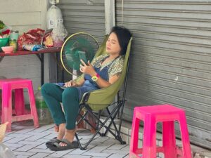 Im Schatten und mit Ventilator: Eine Frau in Bangkok versucht, sich sich abzukühlen.
