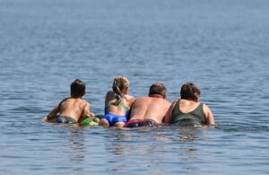 Eine Familie schwimmt auf einer Luftmatratze im Wasser eines Sees.