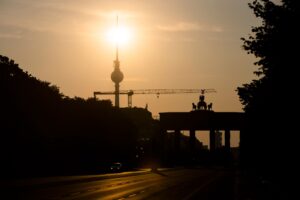 Das Brandenburger Tor und der Fernsehturm sind im Gegenlicht der aufgehenden Sonne zu sehen.