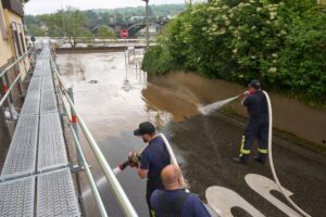 Feuerwehrleute reinigen im Koblenzer Stadtteil Güls die die Straßen vom Schlamm, den das Moselhochwasser zurückgelassen hat.
