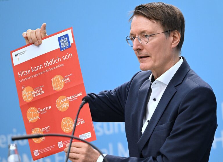 Bundesgesundheitsminister Karl Lauterbach (SPD) hält ein Plakat zum Thema Hitzeschutz hoch.