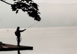 Ein Angler versucht morgens vom Ufer des Baldeneysees aus Fische zu fangen.