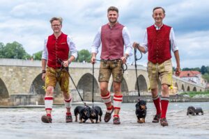 Mit einer Dackelparade wollen die Macher des Dackelmuseums, Oliver Storz (links), Moritz Hickl (Mitte) und Seppi Küblbeck (rechts), auf den kulturellen Wert der Dackelzucht aufmerksam machen.