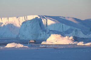 Ein Schiff mit Touristen fährt im Ilulissat-Eisfjord im Westen von Grönland an Eisbergen vorbei.