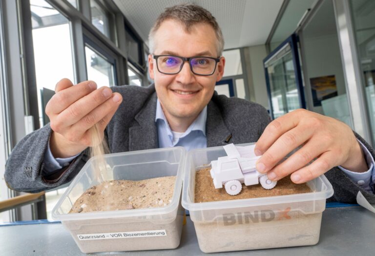Luitpold Fried vom Start-Up-Unternehmen „Bind-X“ zeigt an einem Beispiel, wie mit einem speziellen Bindemittel aus ungefestigtem Sand, eine feste Verbindung entstehen kann, die zur Reduzierung von Staub auf unbefestigten Straßen führt.  Foto: Peter Kneffel/dpa
