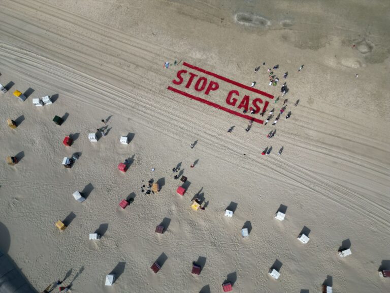 Klimaschutzaktivisten von Fridays for Future schreiben ihre Forderung nach einem Ende der Gasförderung auf den Strand der Insel Borkum.  Foto: Lars Penning/dpa